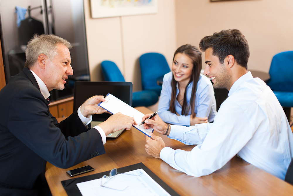Businessman showing document to a couple Senior businessman showing a document to sign to a couple